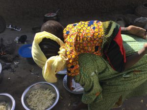 Preparing rice with child on back