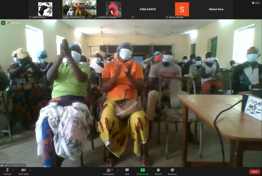 a group adults sit in a room wearing masks and clapping during a presentation. this is outside of youth development