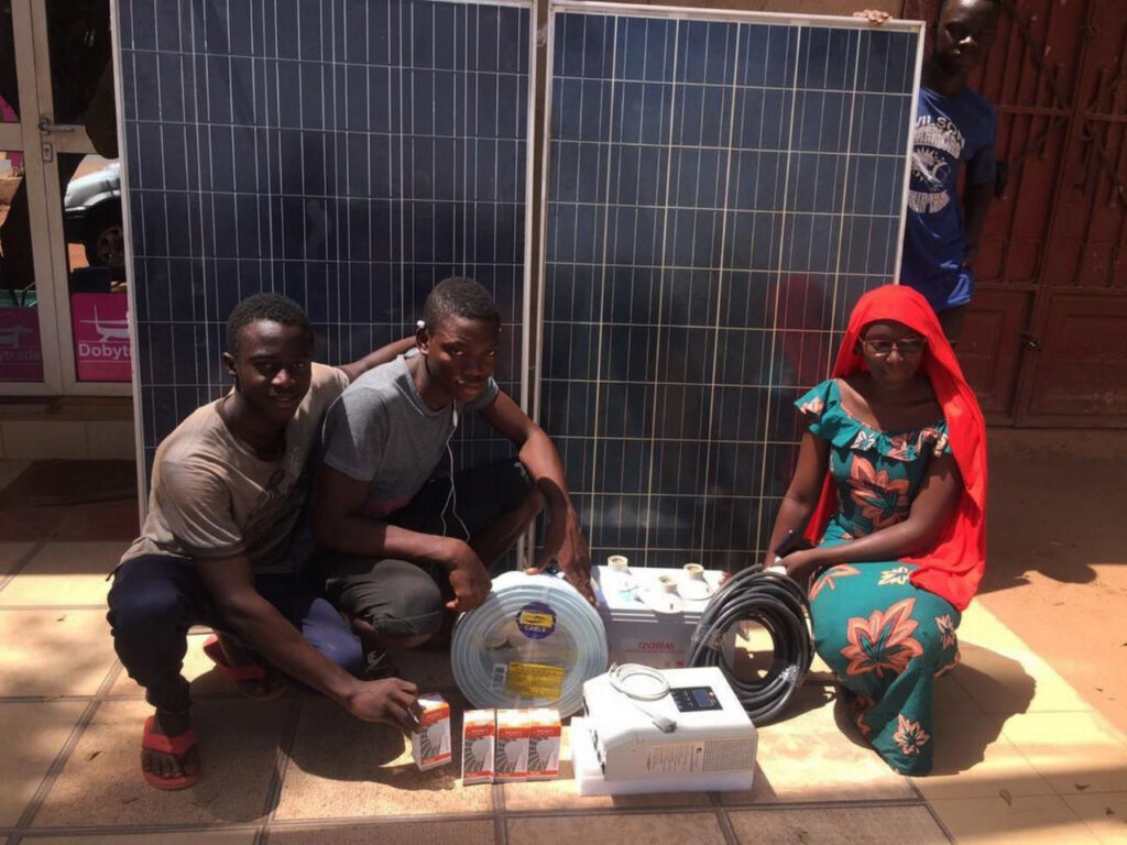 four youth pose next to solar equipment
